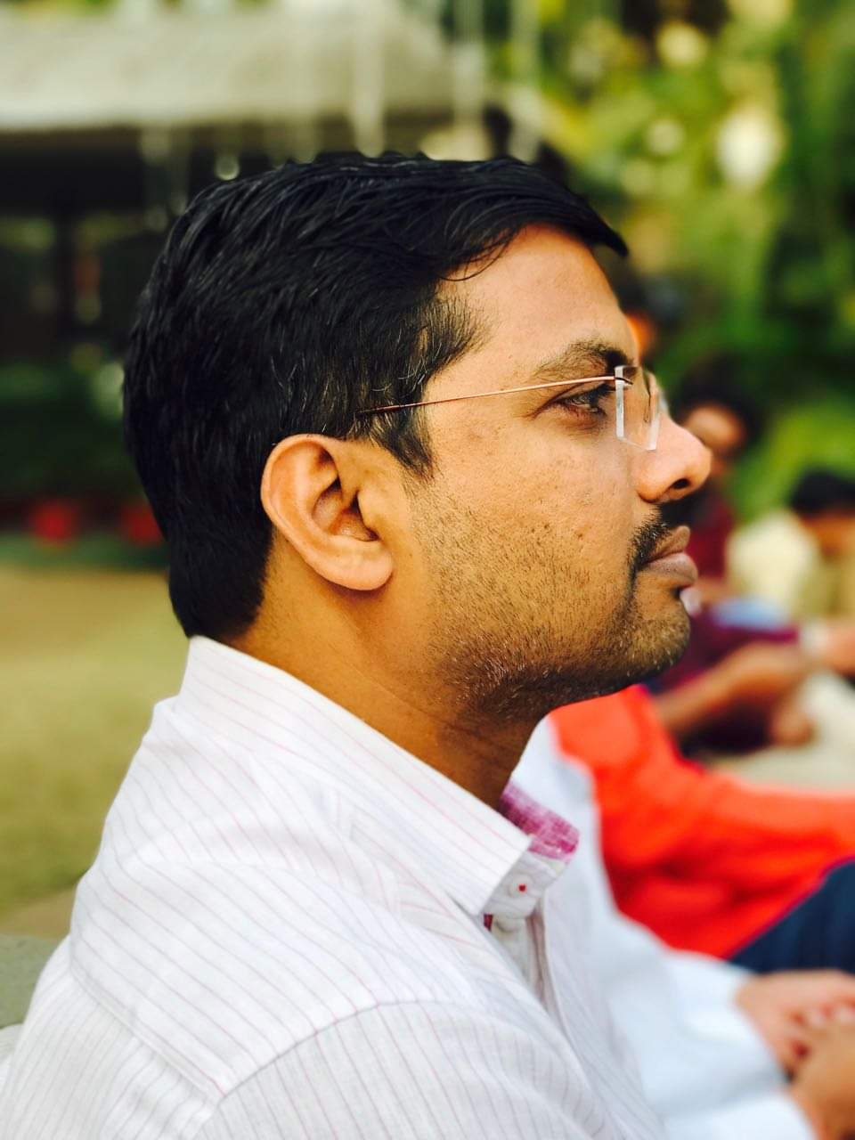 A classroom with students raising their hands and a teacher in the background